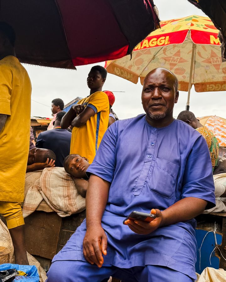 A busy Nigerian market with vendors under colourful umbrellas
