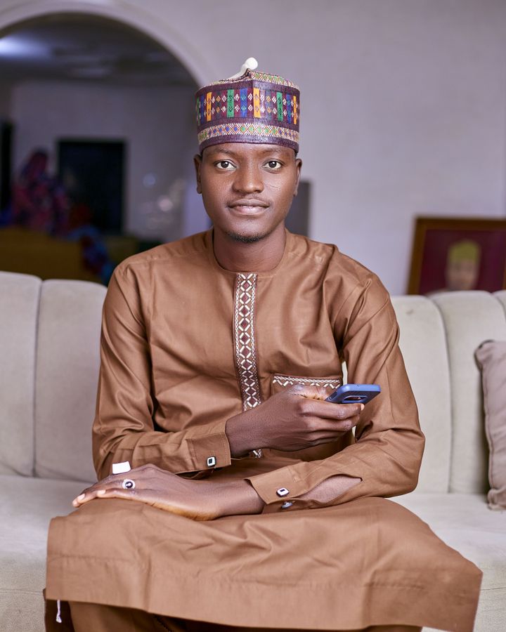 A young man in traditional attire relaxing on a couch with his phone